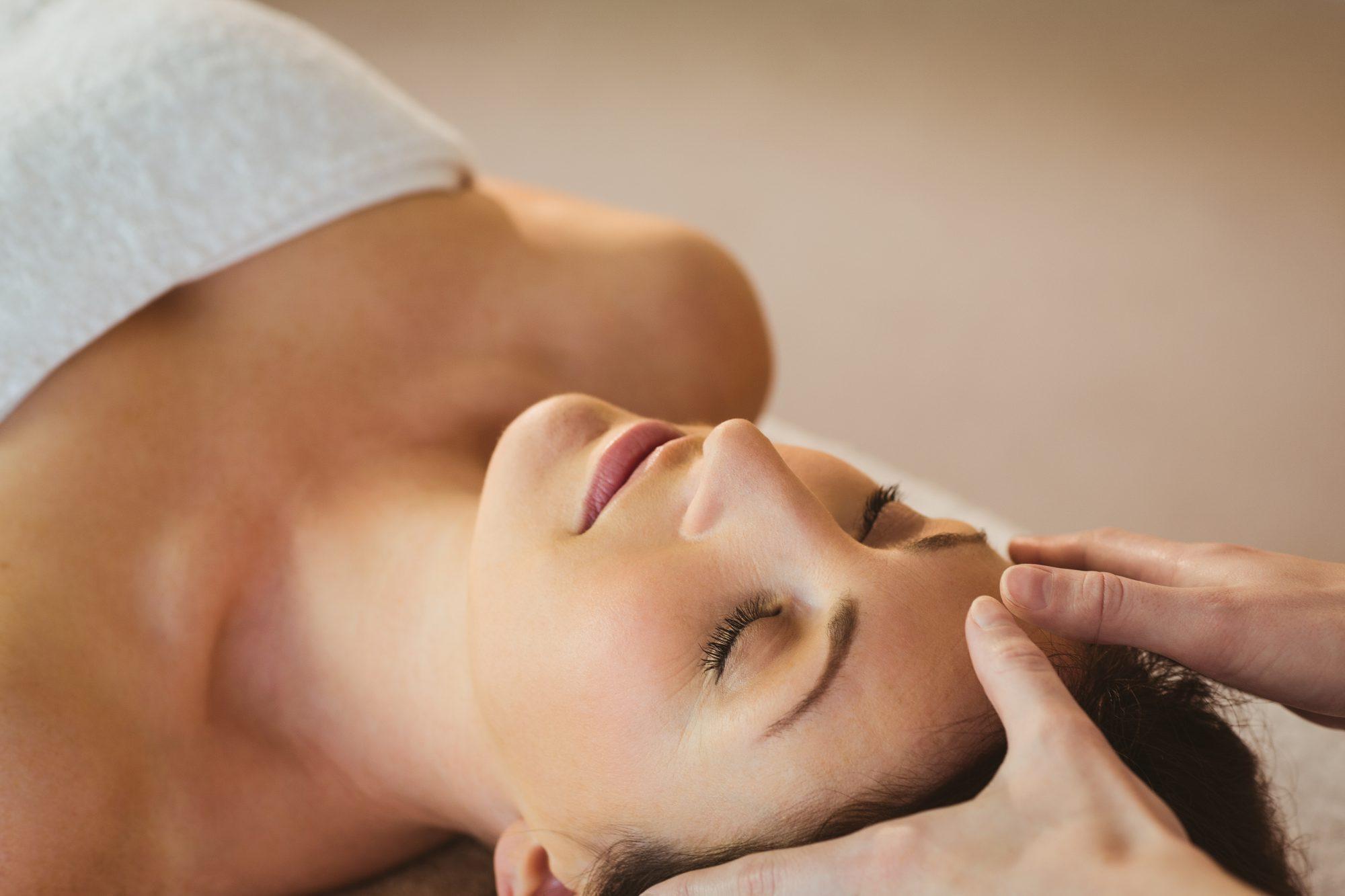 Young woman having a reiki treatment in therapy room